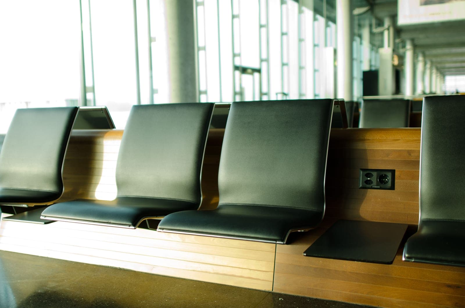 An empty airport departure gate seating area with sunlight coming through the windows