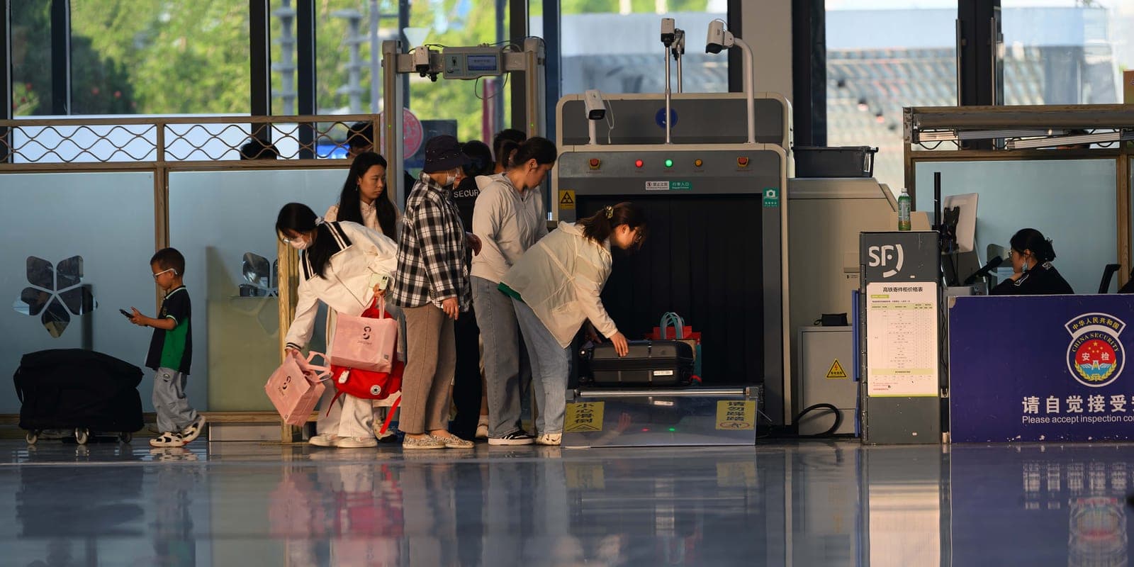 Passengers moving through a security screening line at an airport terminal