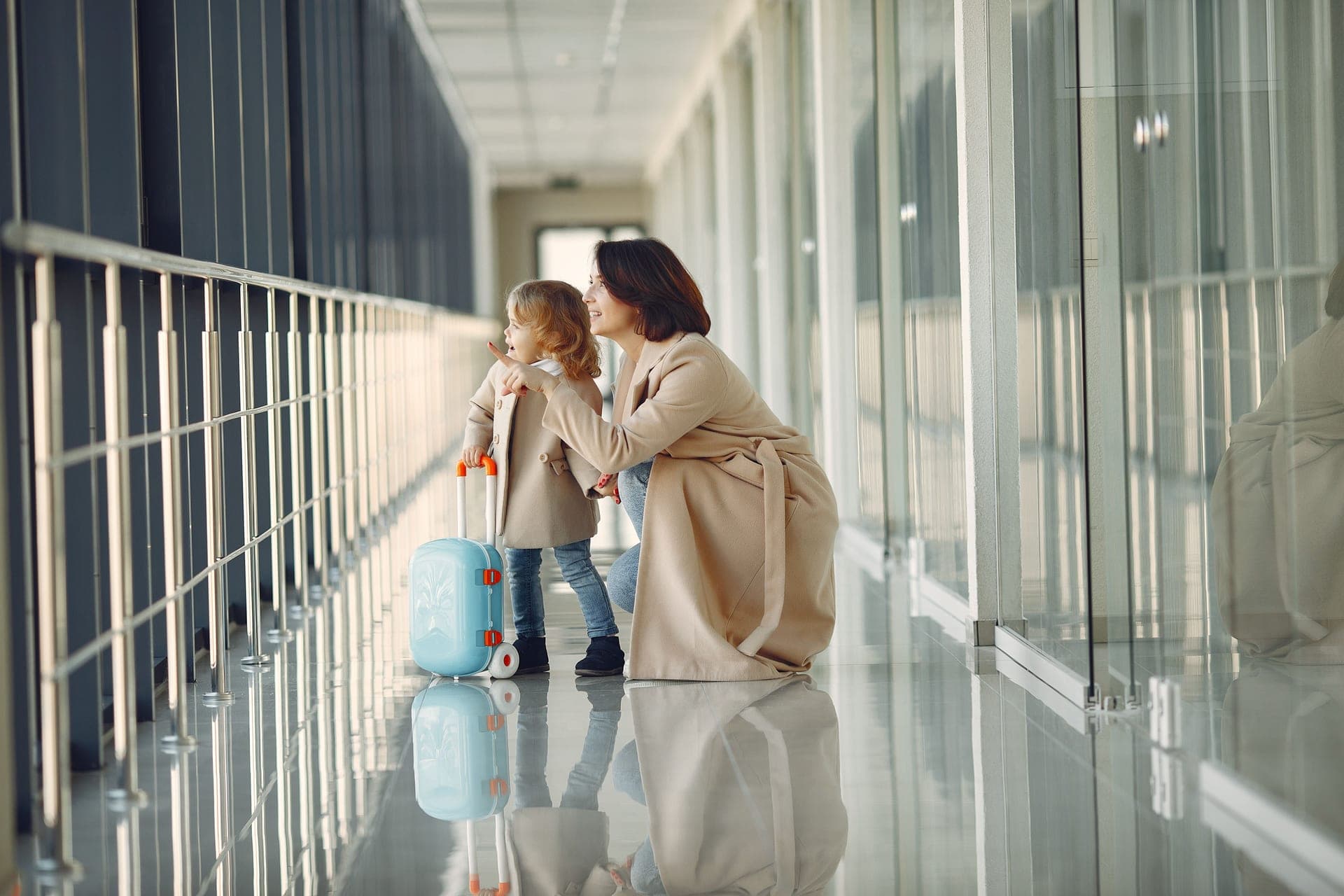 A small child pulling a suitcase through an airport concourse