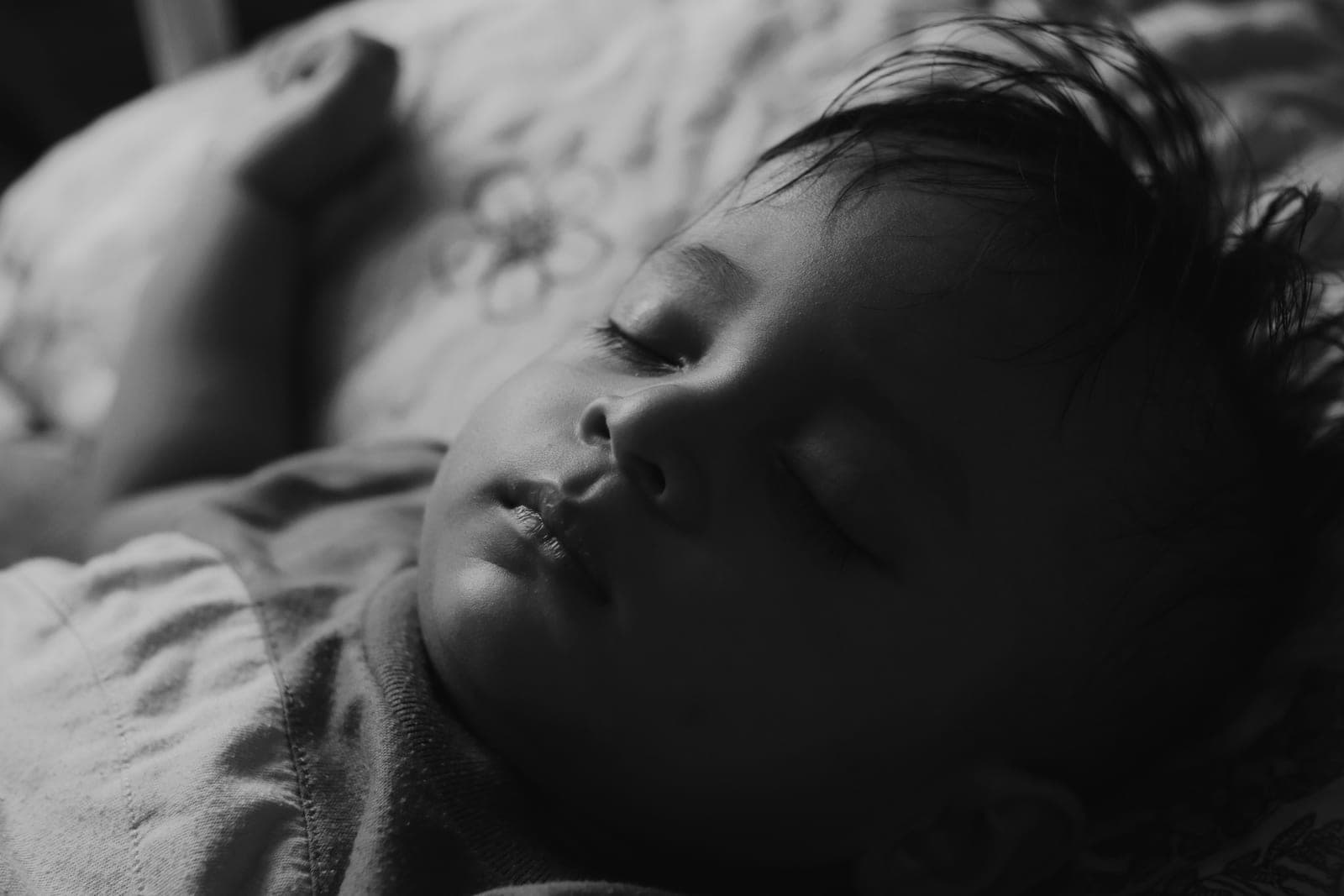 A young child asleep on a bed in a dim room