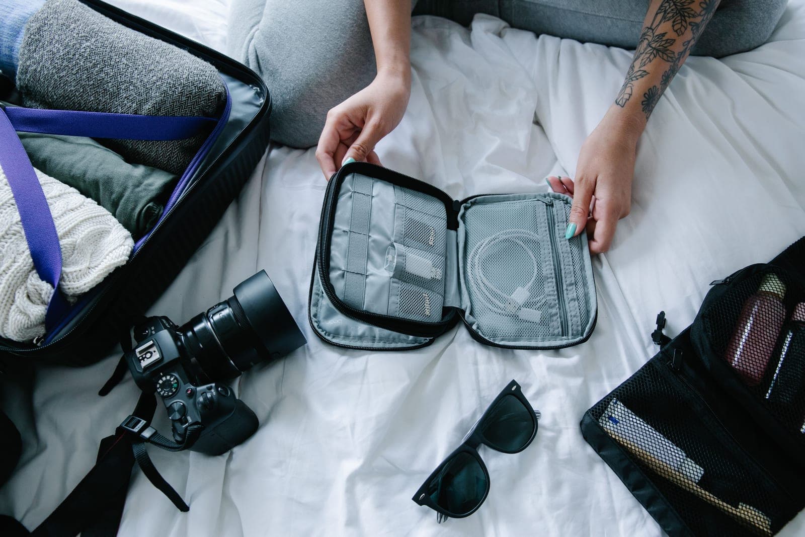 A traveler organizing packing cubes and essentials on a hotel bed
