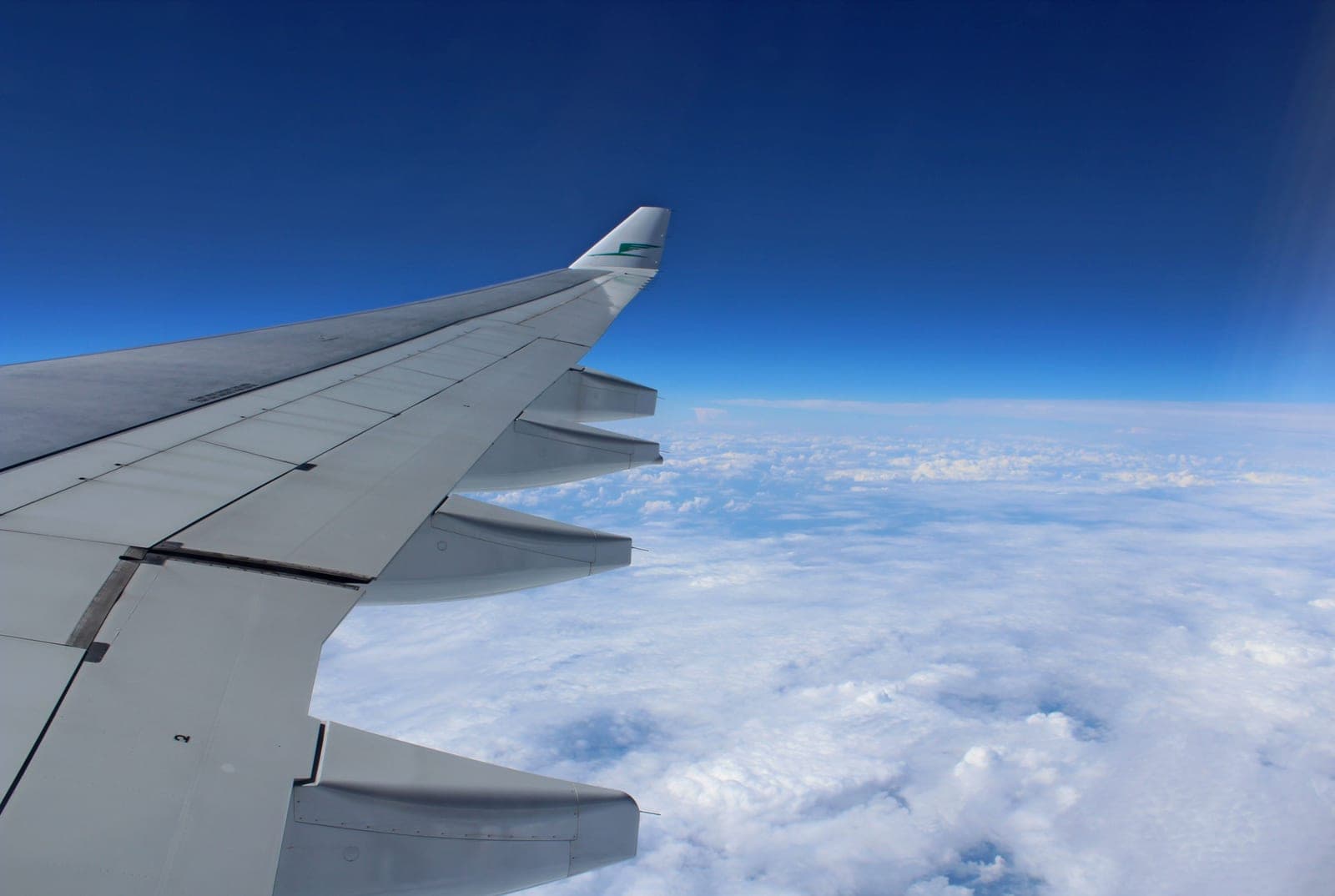 An airplane wing seen from a cabin window above the clouds