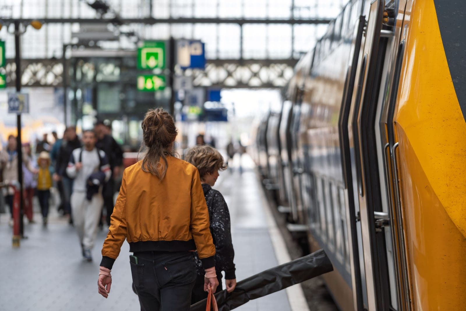 A parent and child boarding a train at a busy station