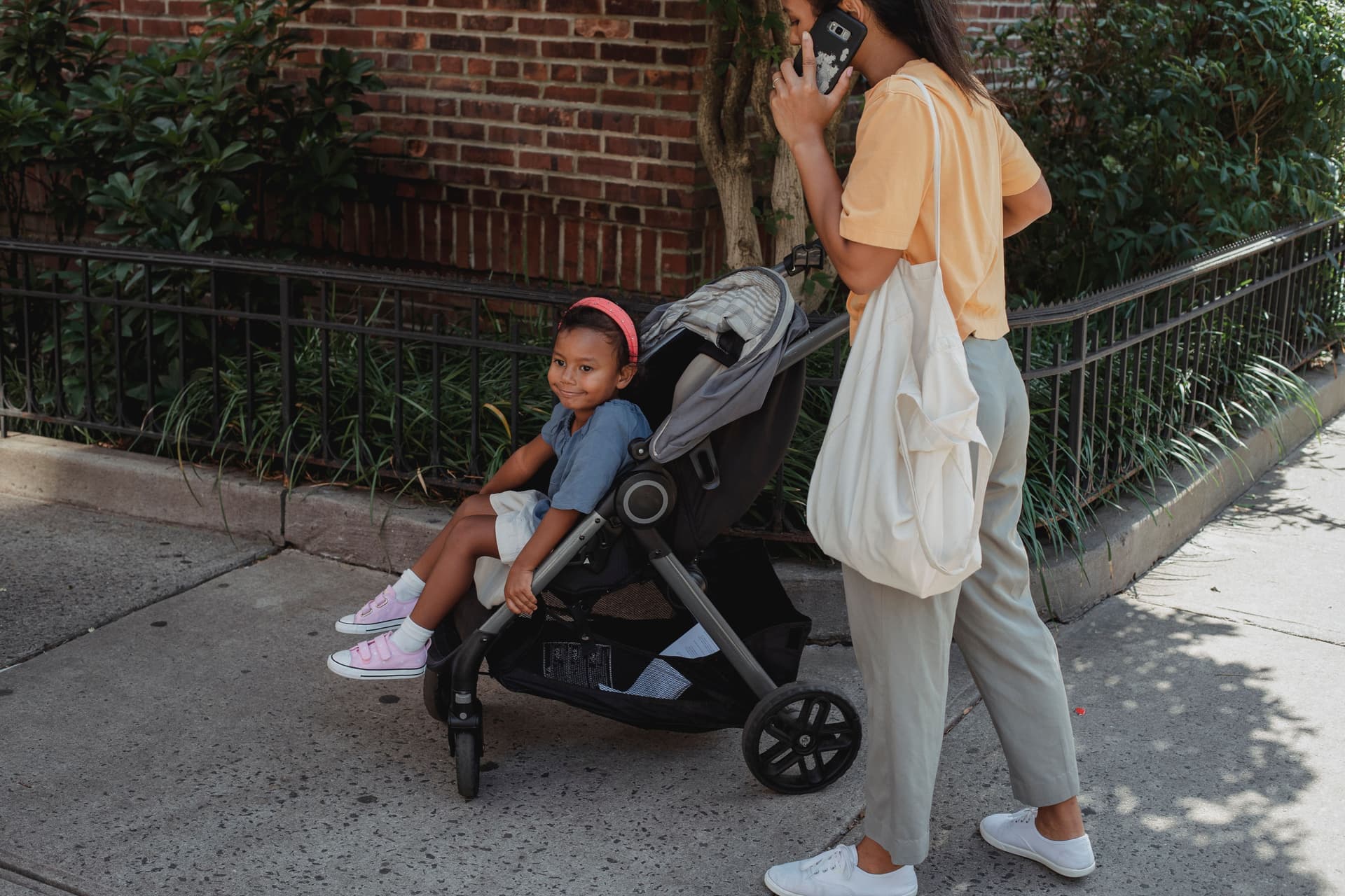A parent pushing a stroller along a city sidewalk